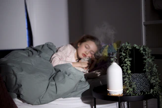 a woman laying in bed with a humidifier next to her