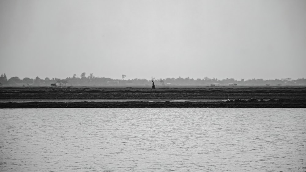 a black and white photo of a person flying a kite