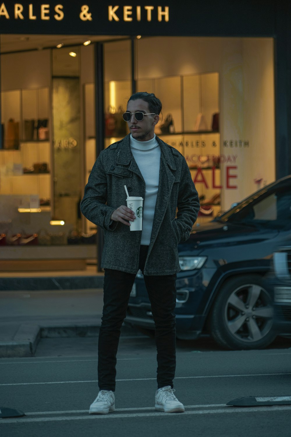 a man standing on a street corner holding a cup of coffee