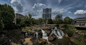 a waterfall in the middle of a river with a city in the background