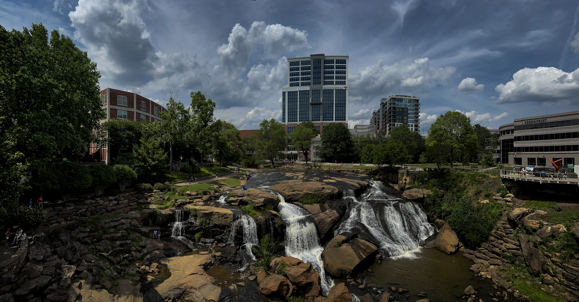 a waterfall in the middle of a river with a city in the background