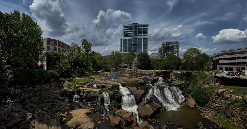 a waterfall in the middle of a river with a city in the background