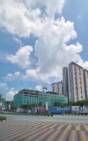 A project manager reviewing blueprints on a busy construction site with cranes and workers in the background.