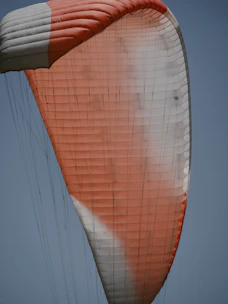 Close-up of a colorful parachute canopy fully deployed over a green dropzone.
