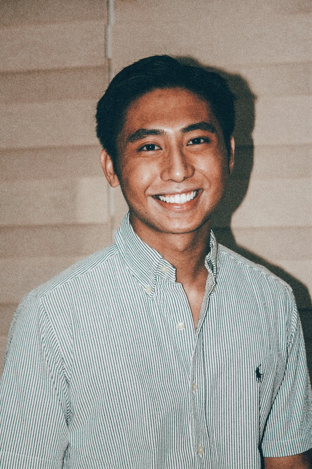 a man in a blue and white shirt smiles at the camera