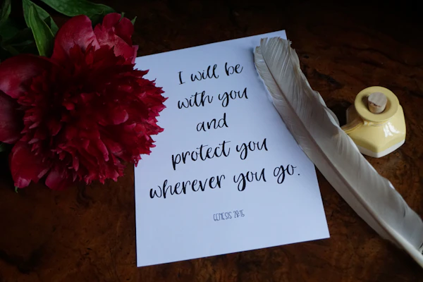 a note with a pen and a flower on a table
