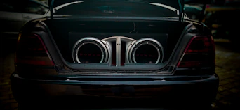 the rear end of a black car with chrome exhaust pipes