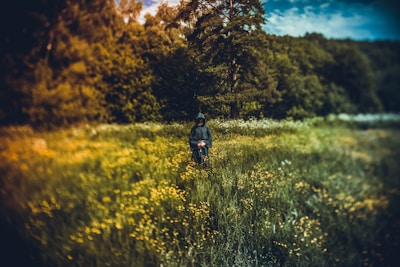a man riding a bike through a lush green field
