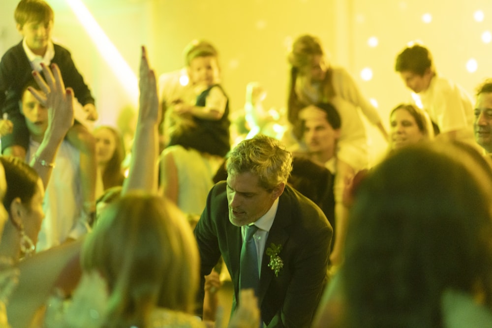 a man in a suit and tie standing in front of a crowd of people