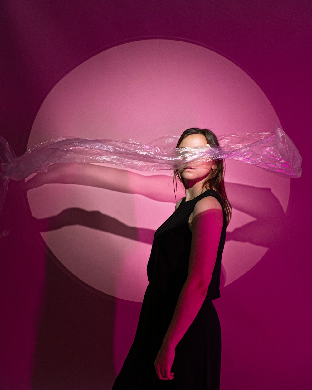 a woman standing in front of a pink background