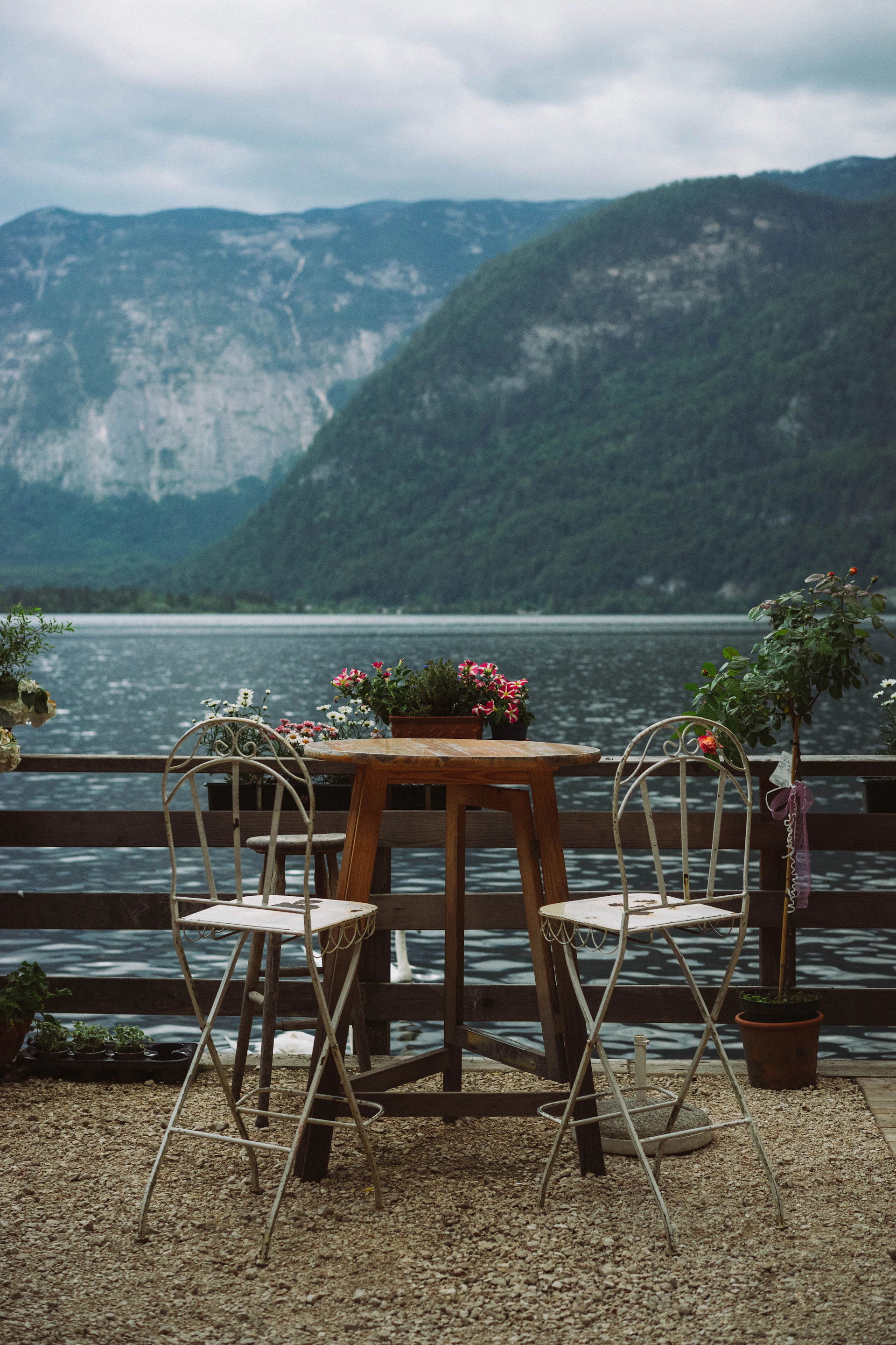 a wooden table with two chairs next to a lake