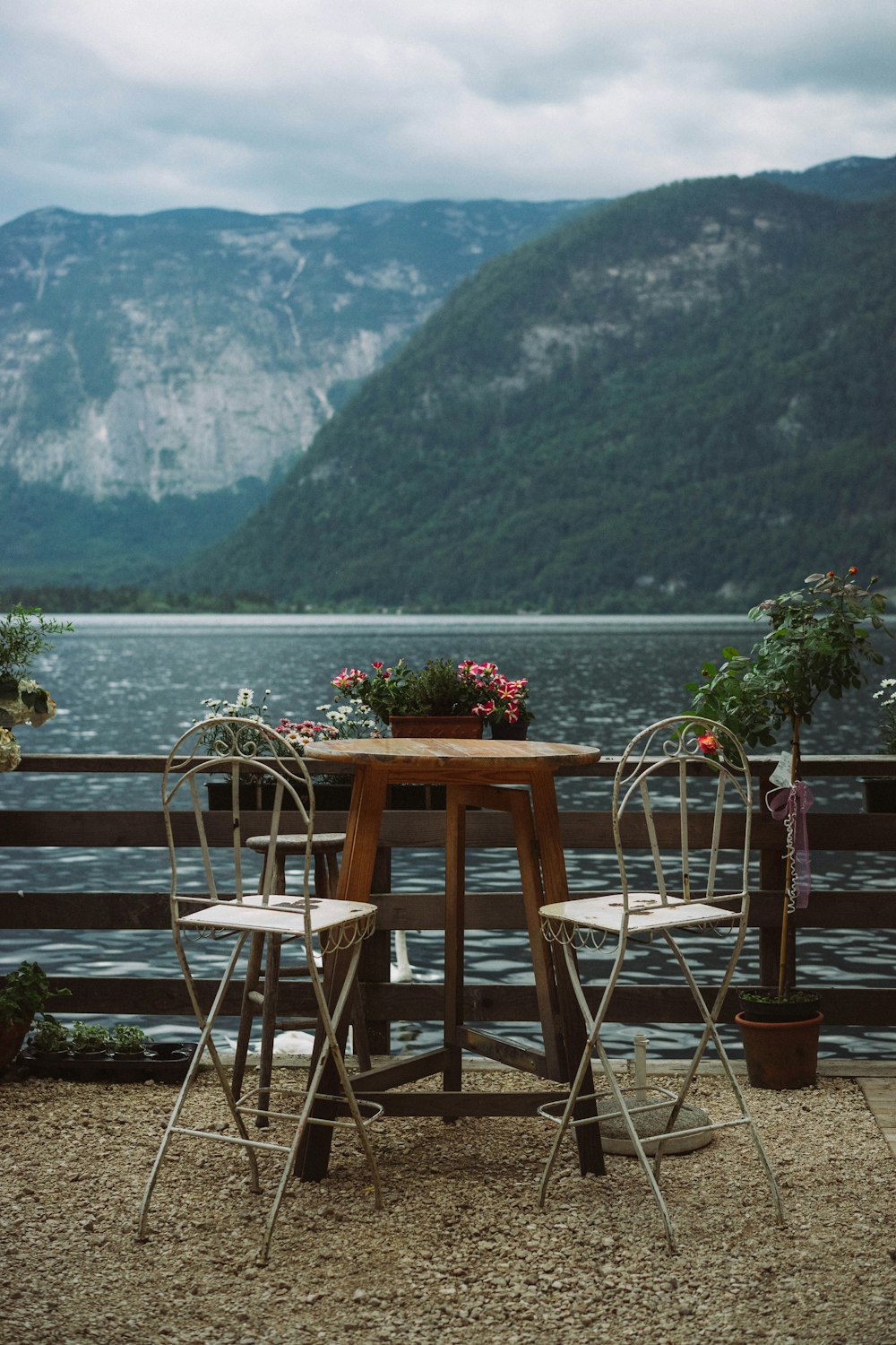 a wooden table with two chairs next to a lake