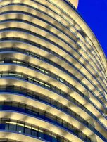 A high-rise apartment building with illuminated windows and a sleek, contemporary design against a night sky.