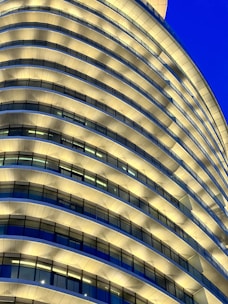 Exterior view of a sleek high-rise tower with double-height living spaces at dusk.