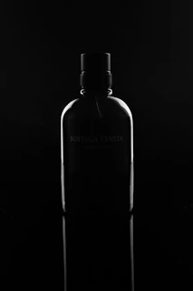 Close-up of a sleek Vivenssi perfume bottle with elegant minimalist design on a dark blue background.