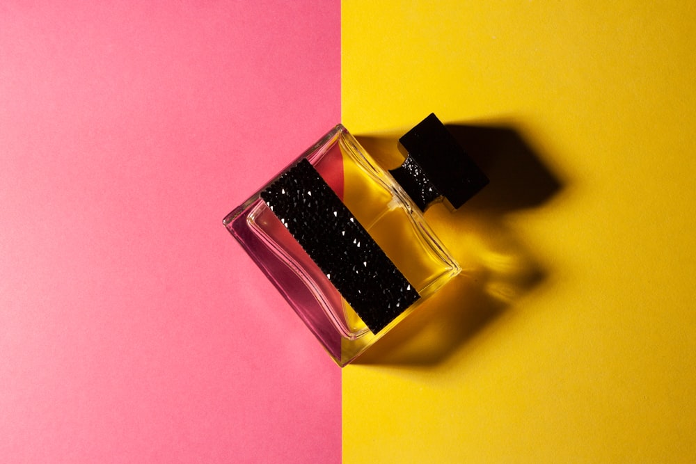 a bottle of perfume sitting on top of a pink and yellow table