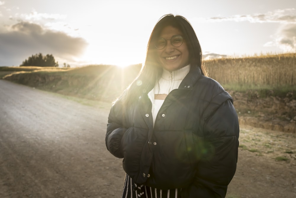 a woman standing in the middle of a dirt road