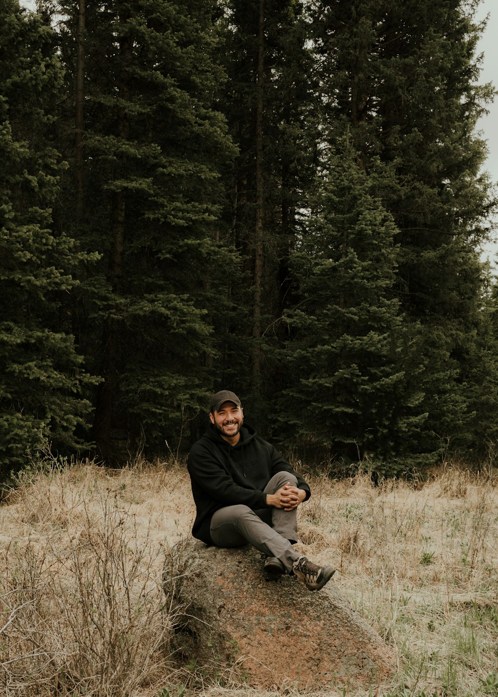 a man sitting on top of a rock in a field