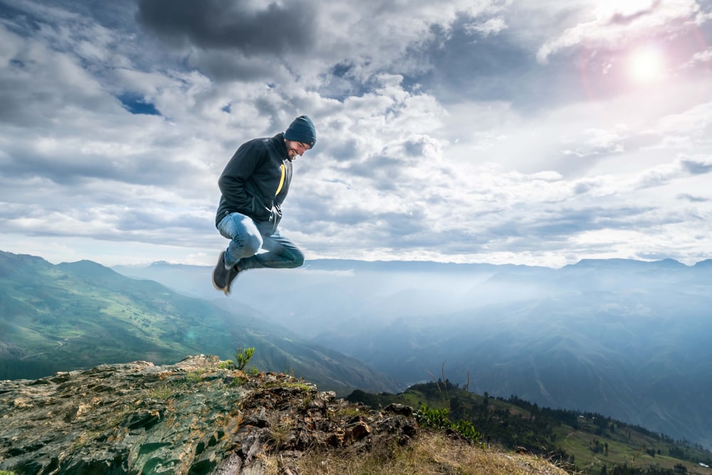 a man jumping in the air on top of a mountain