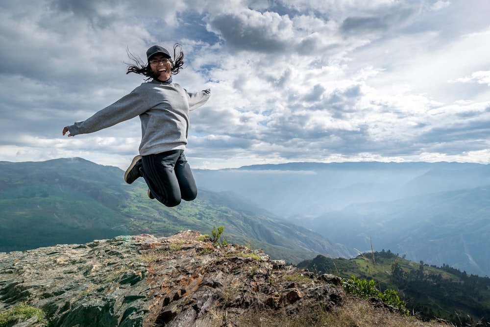 a person jumping in the air on top of a mountain