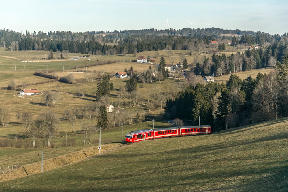 a red train traveling through a lush green countryside