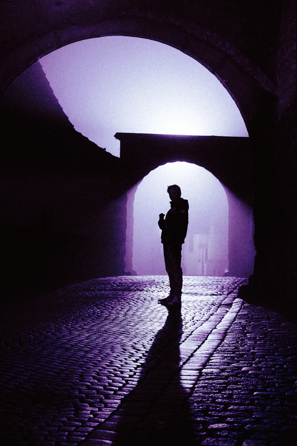 a silhouette of a person standing in a tunnel