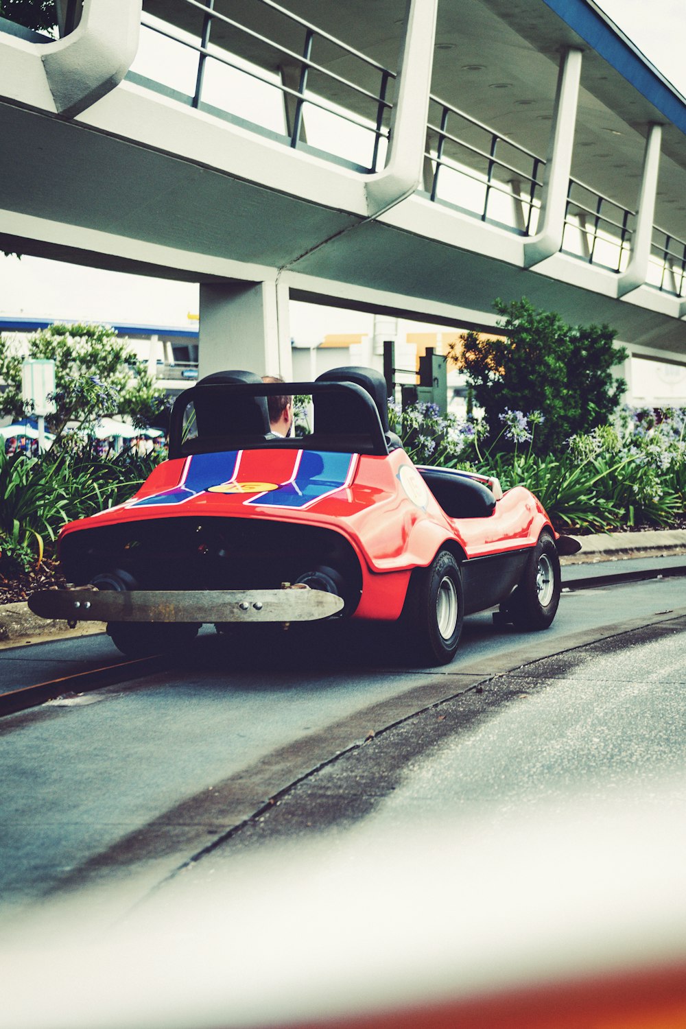 a red and blue car driving down a street next to a bridge