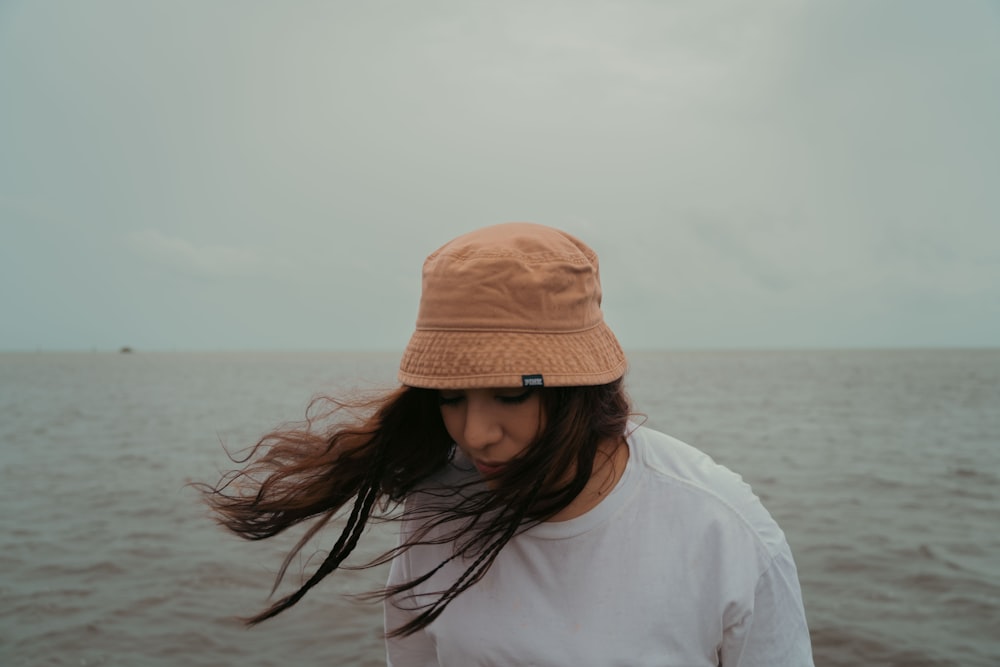 a woman with long hair standing in front of a body of water