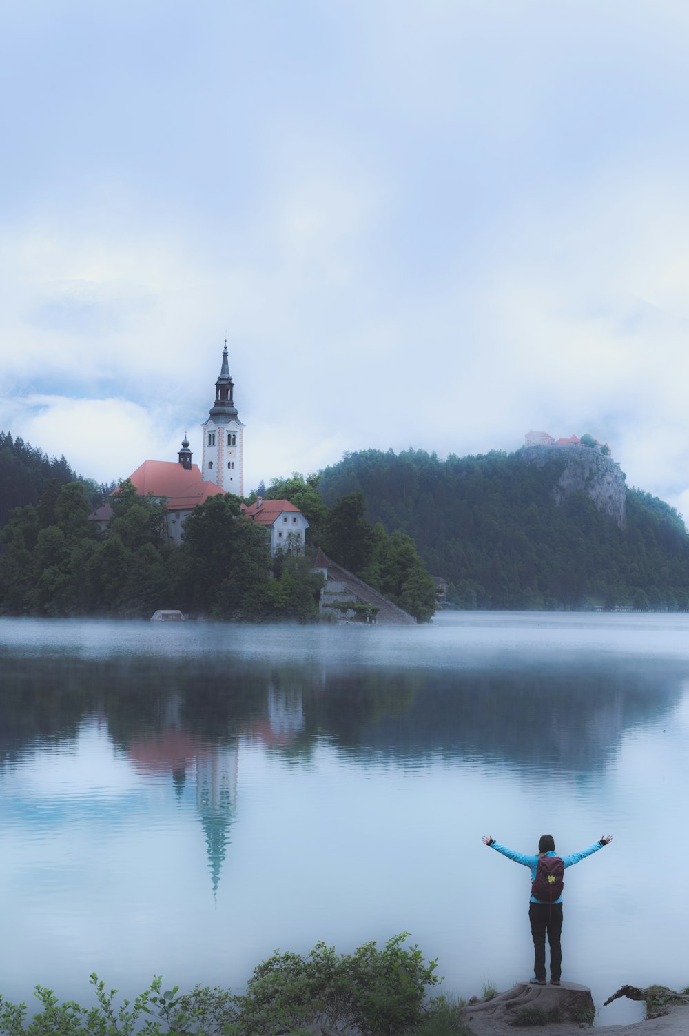 a person standing on a rock in front of a lake