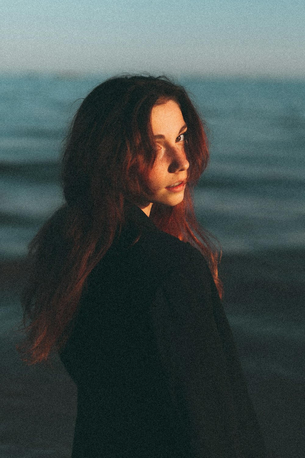 a woman standing in front of a body of water