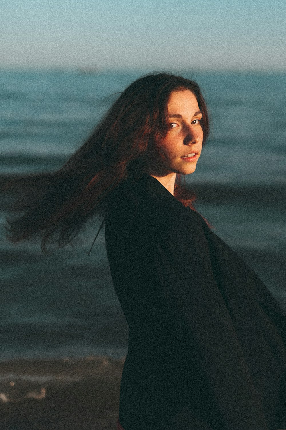 a woman standing on a beach next to the ocean