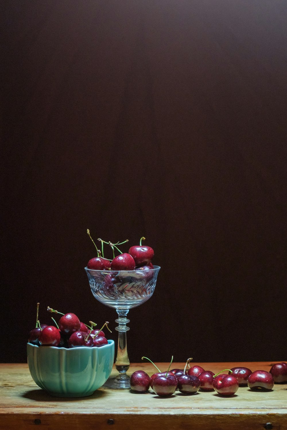 a table topped with a bowl of cherries next to a bowl of cherries
