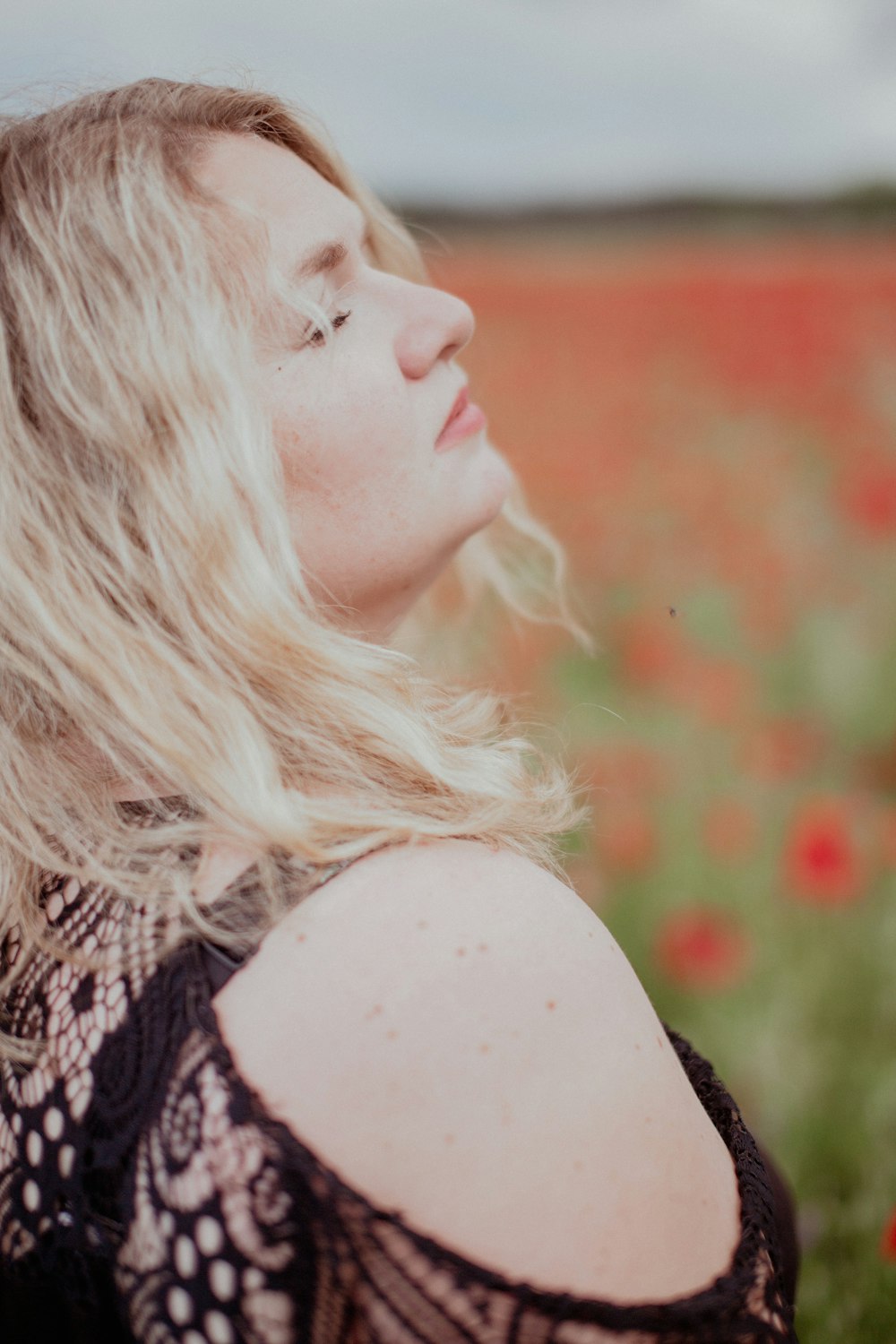 a woman standing in a field of red flowers