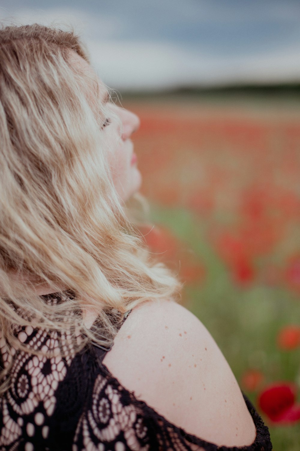 a woman standing in a field of red flowers