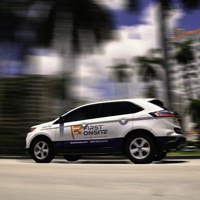 a white car driving down a street next to tall buildings