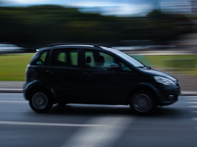 Small black car driving down a street