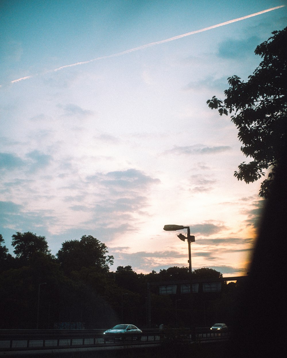 a car driving down a road under a cloudy sky