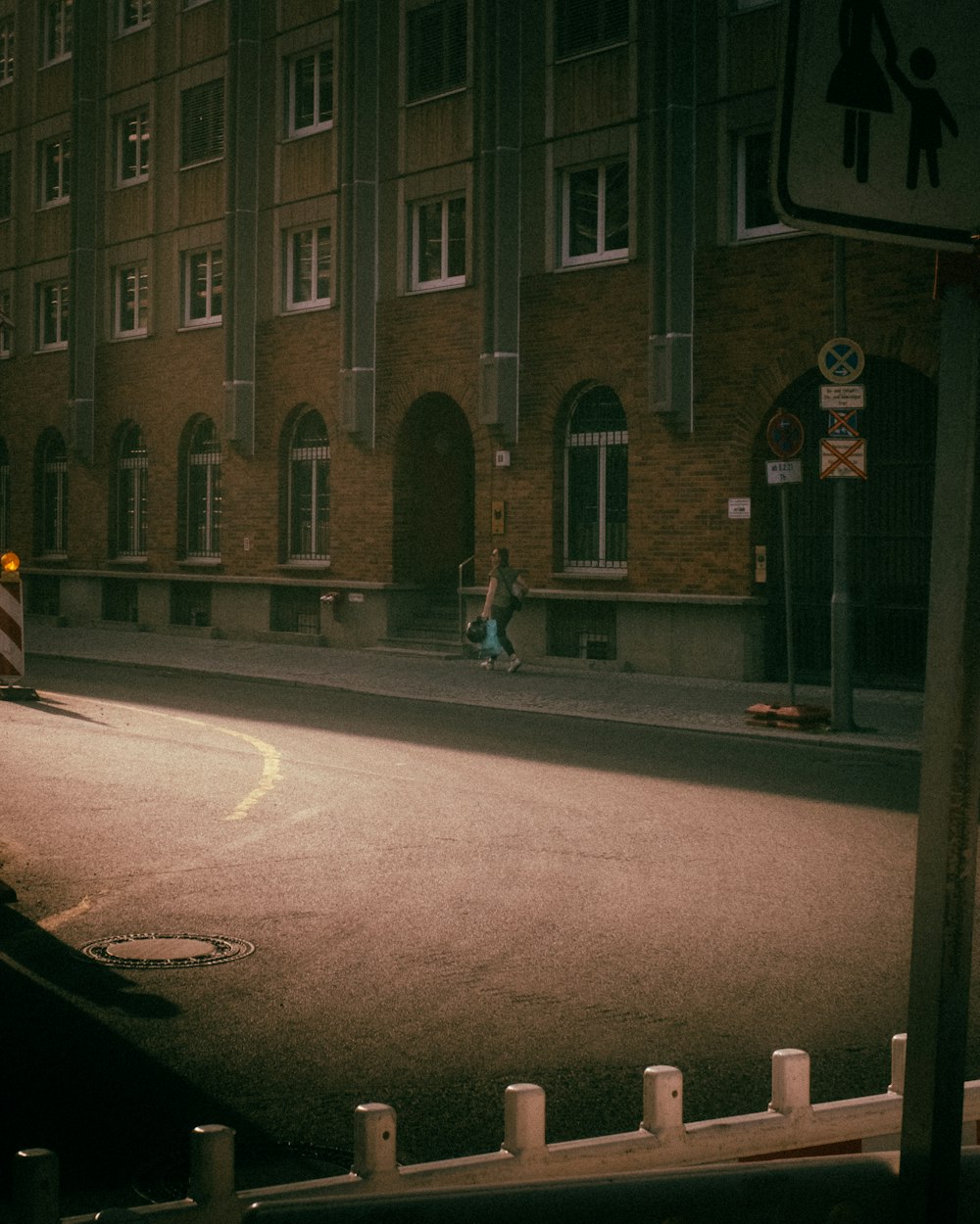 a person walking down a street next to a tall building