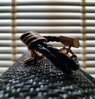 Classic cufflinks placed beside a folded dress shirt on a wooden desk.