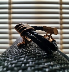 Close-up of luxurious gold cufflinks and a dark silk tie on a wooden surface.