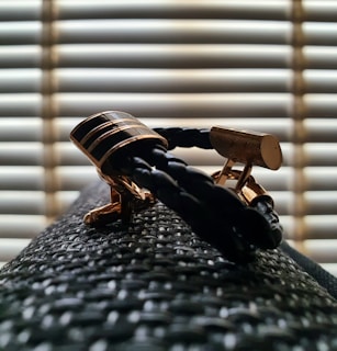 Classic cufflinks placed beside a folded dress shirt on a wooden desk.