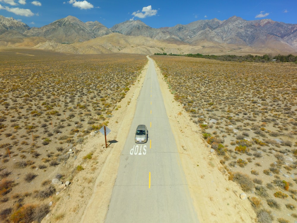 a car driving down a road in the middle of the desert