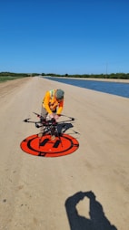 a man working on a red and black sign on a beach