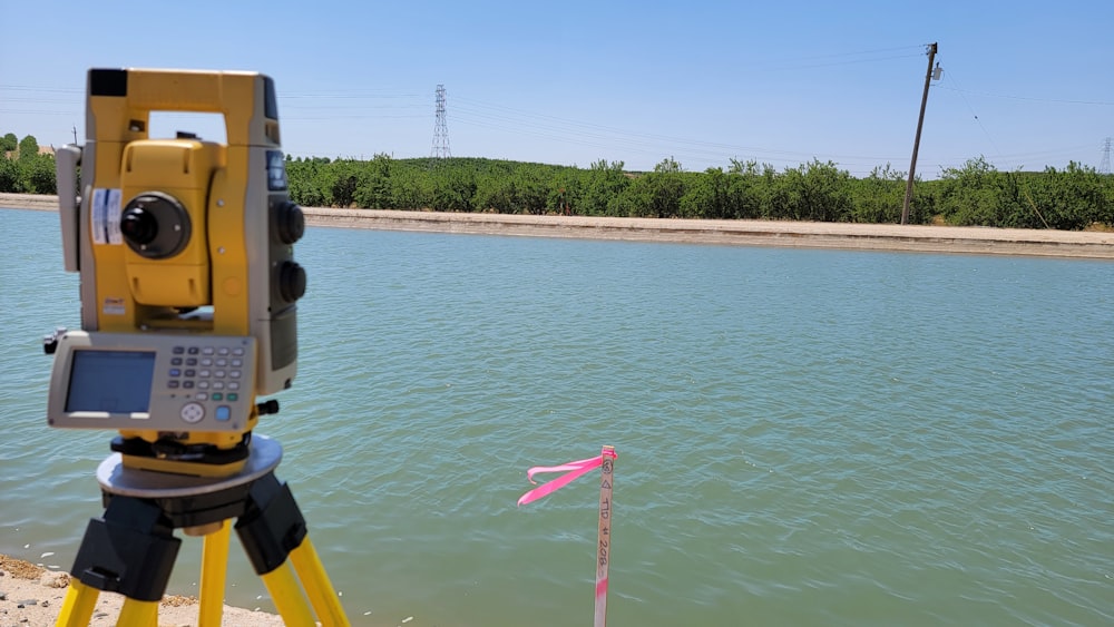 a yellow tripod with a camera on top of it near a body of water