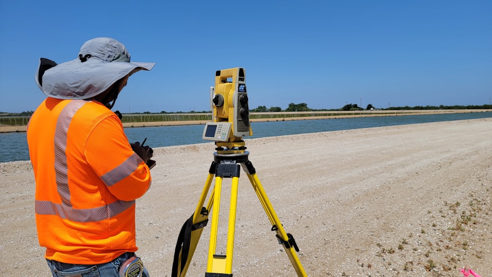 a man standing next to a yellow and black tripod