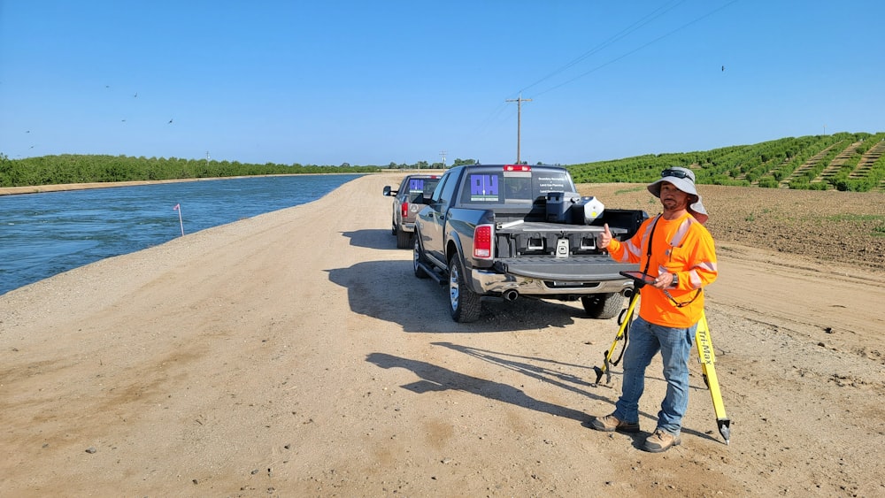 a man standing next to a truck on a dirt road