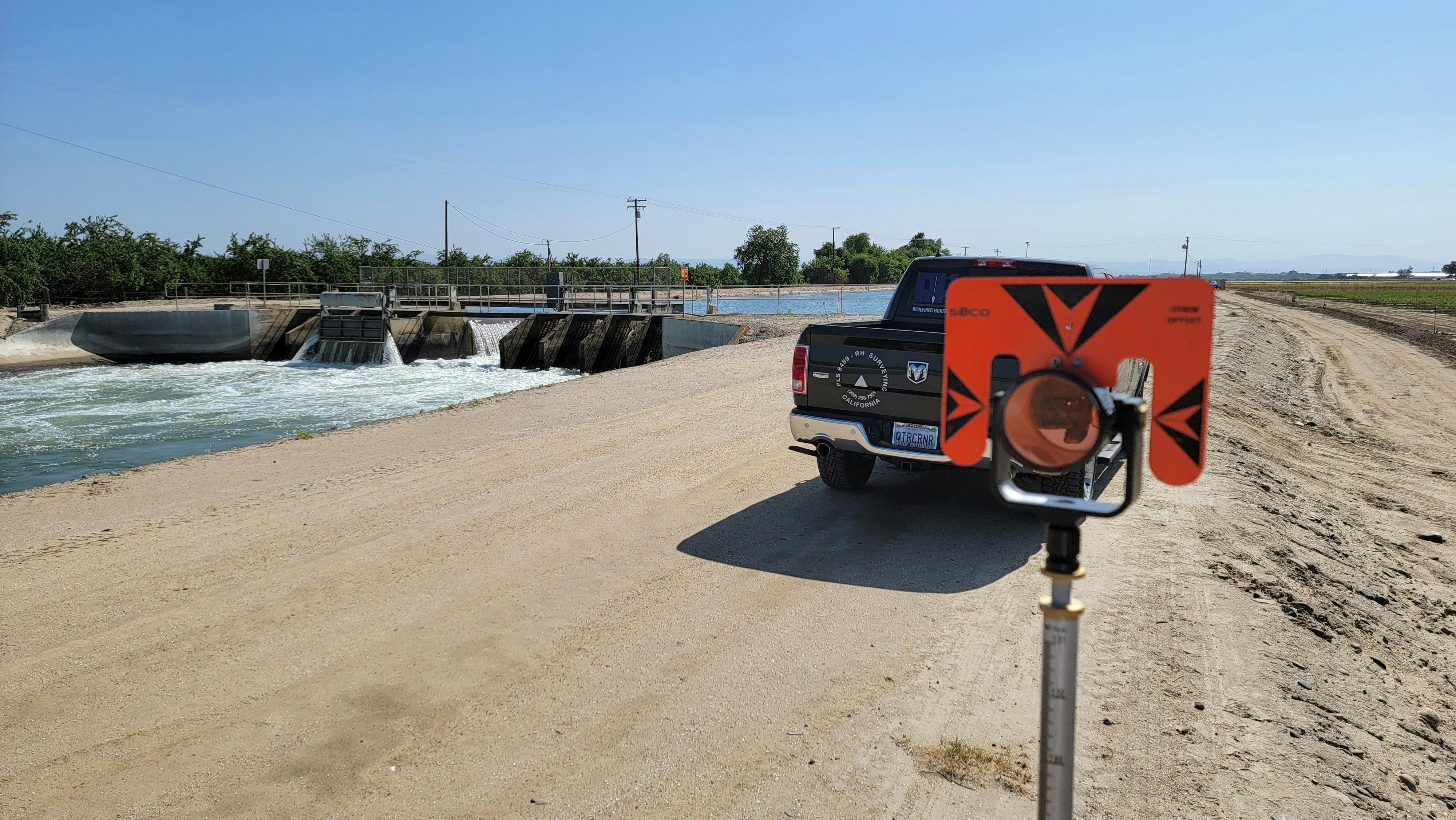 a truck driving down a dirt road next to a body of water