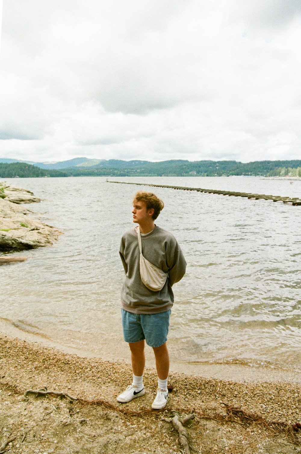 a man standing on a beach next to a body of water