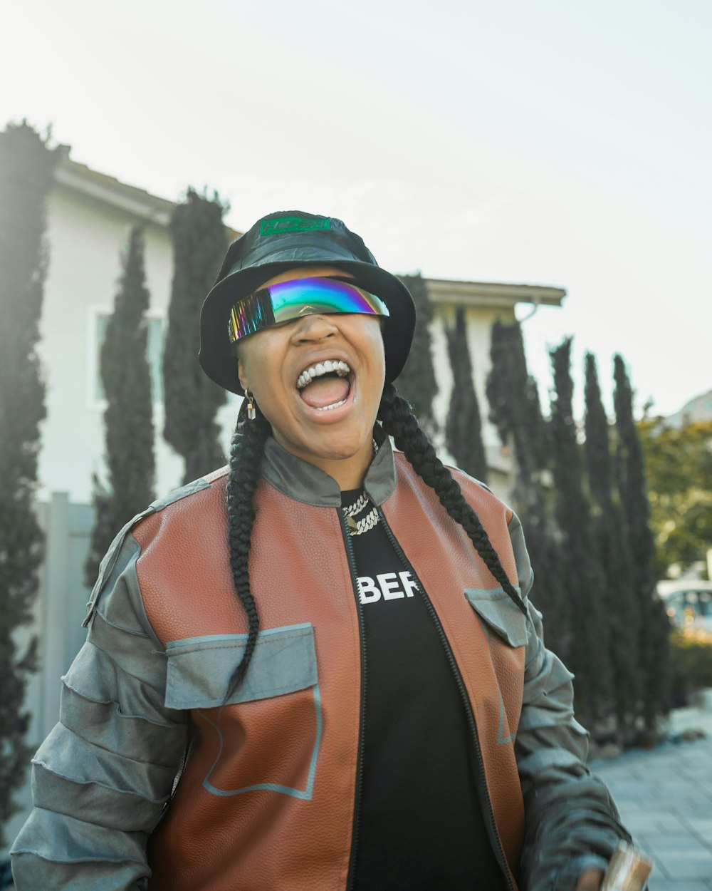a woman in a leather jacket and hat laughing