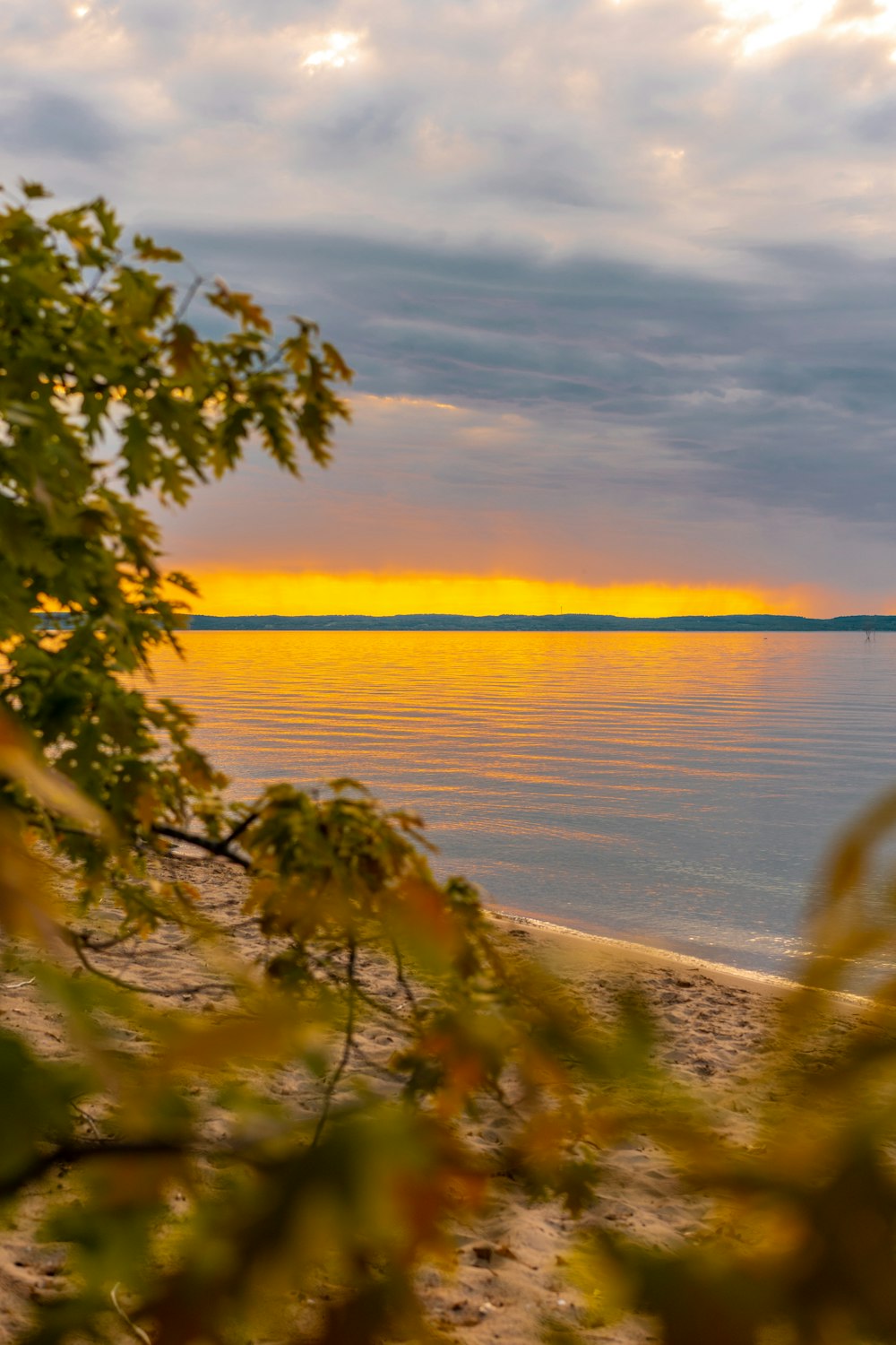 the sun is setting over the water at the beach